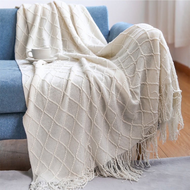 LEDSone affordable luxury throw blanket in cream draped over a blue sofa with a cup of tea