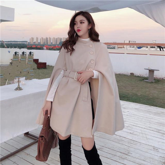 Womens beige cape coat with belted waist and button detail by Côte & Crown styled with black boots