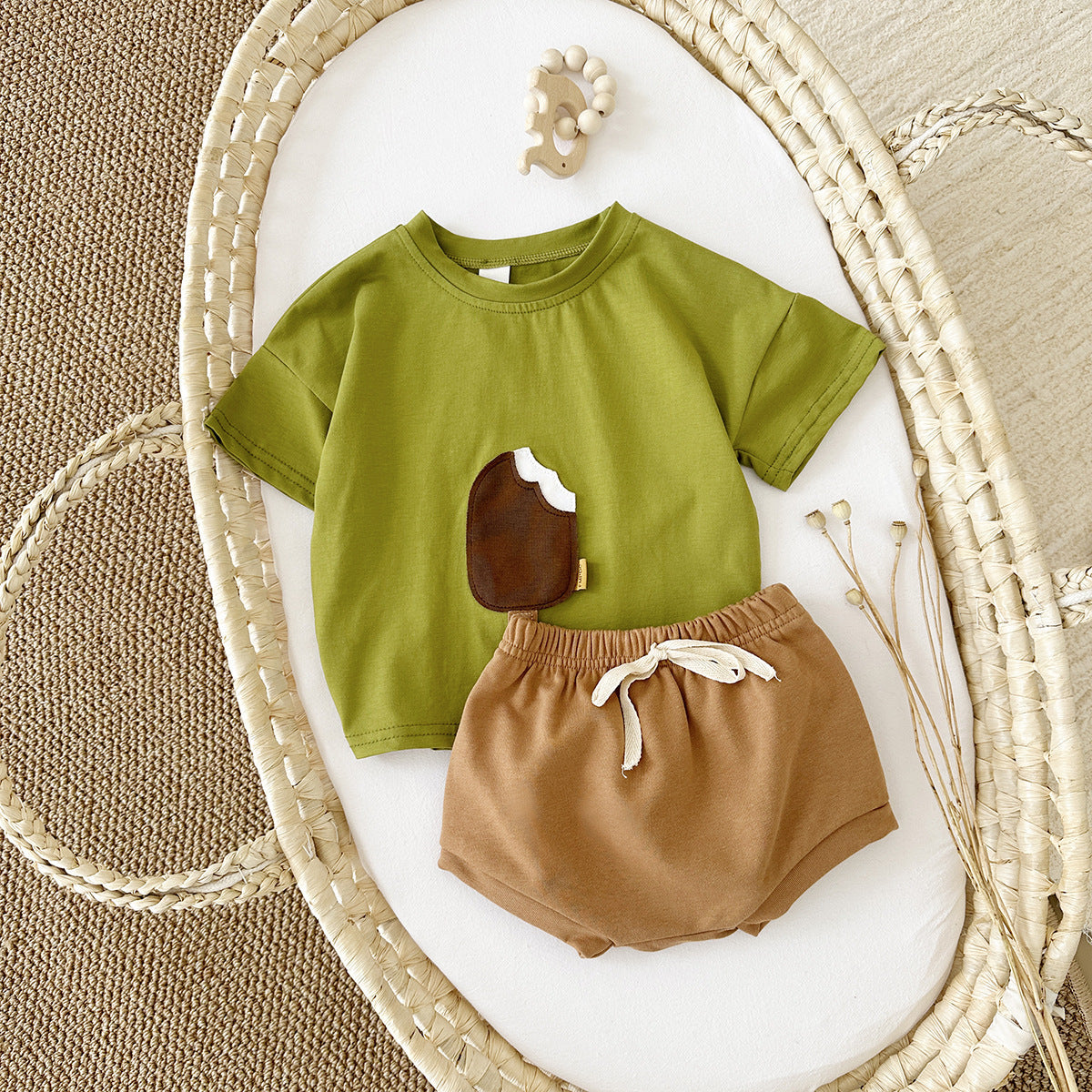 Côte & Crown baby clothes set with green ice cream graphic t-shirt and brown shorts on woven mat