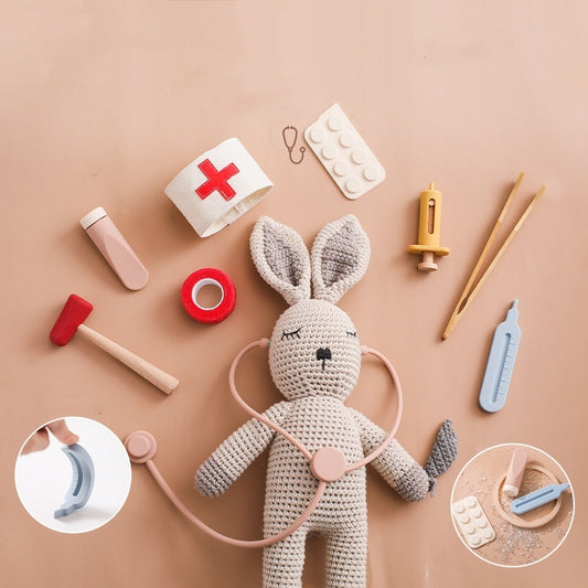 Côte & Crown children's doctor play set with crocheted bunny and various medical toy tools on beige background