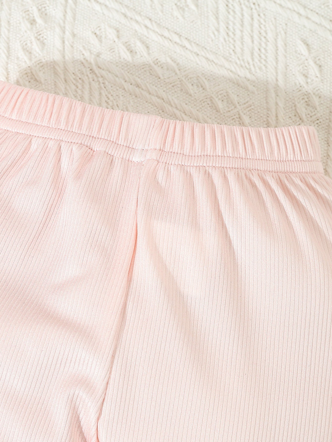 Close-up of pink ribbed pants from infant printed 3 piece outfit by Côte & Crown for baby girls