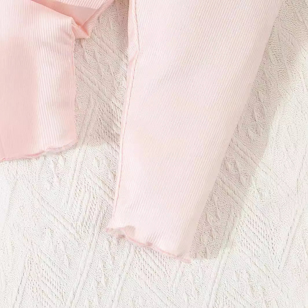 Infant printed 3 piece outfit pink ribbed fabric close-up on textured white background