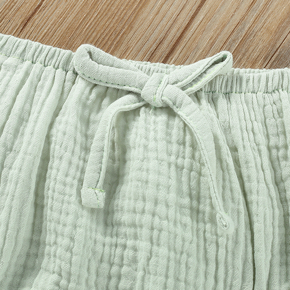 Close-up of green cotton fabric detail with bow on girls summer sling top and shorts set by Côte & Crown