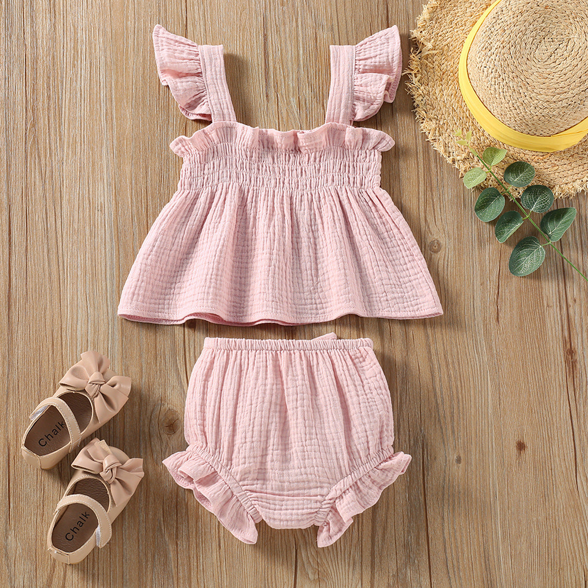 Pink girls summer sling top and shorts set by Côte & Crown with ruffle details on wooden background