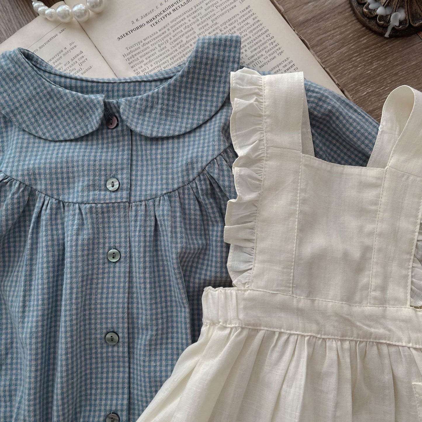 Côte & Crown ruffled baby romper dress in cream with a blue checkered button-up baby romper