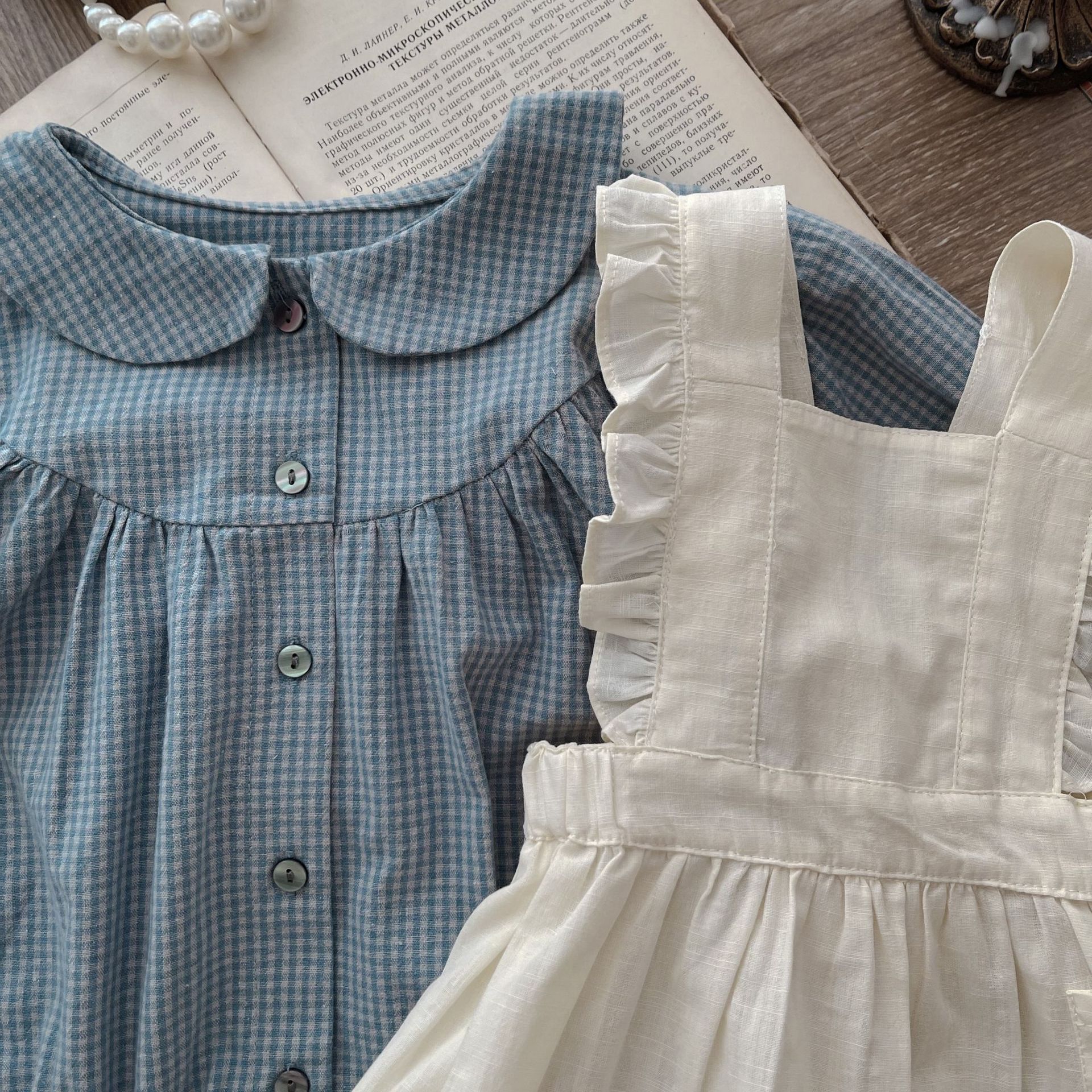 Côte & Crown ruffled baby romper dress in cream with a blue checkered button-up baby romper