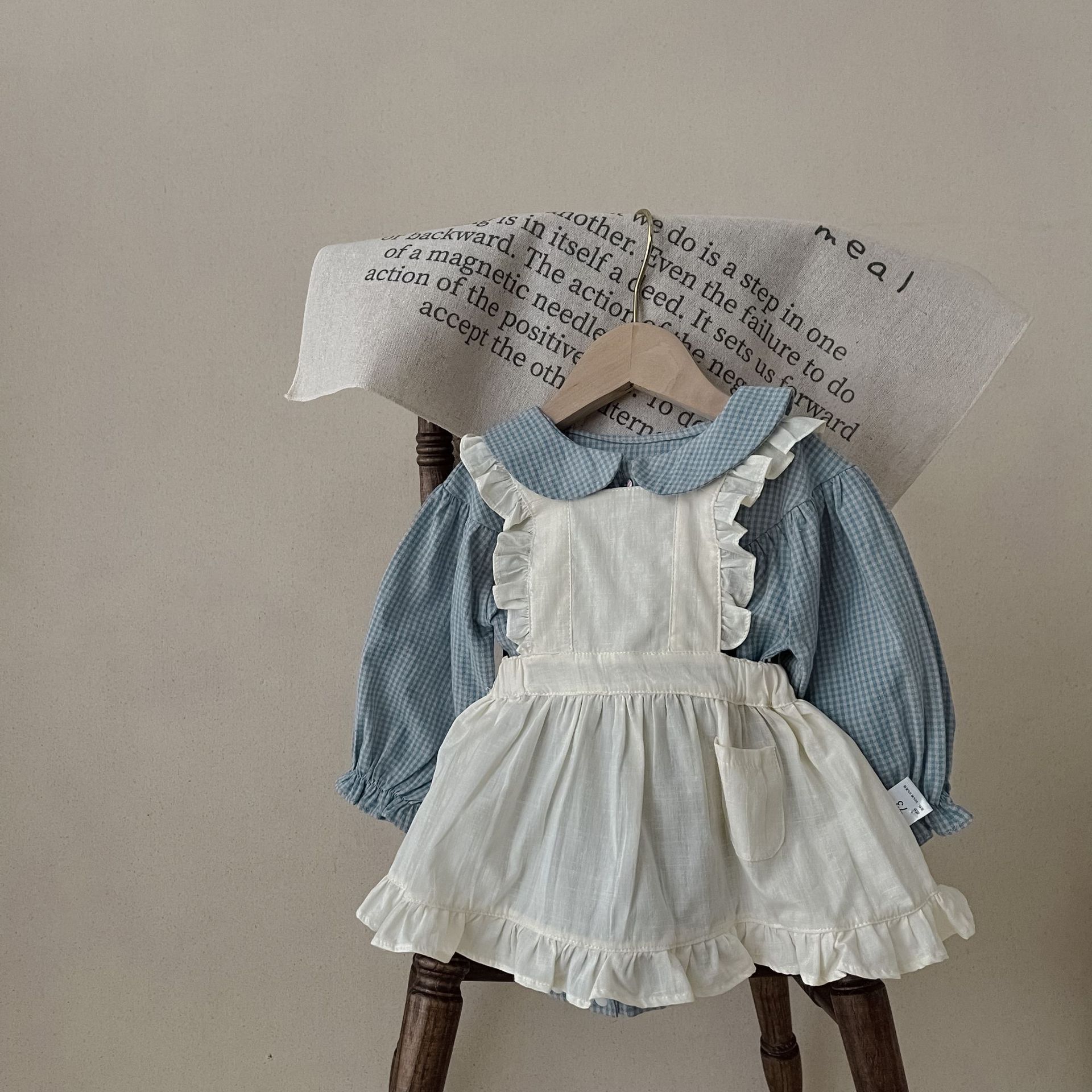 Côte & Crown ruffled baby romper dress in blue with white apron-style ruffle detailing