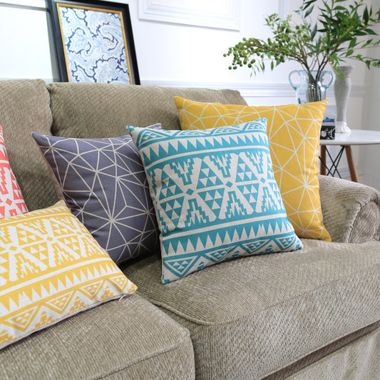 Côte & Crown soft furnishing decorative cushions with geometric patterns in yellow, blue, grey and coral on beige sofa