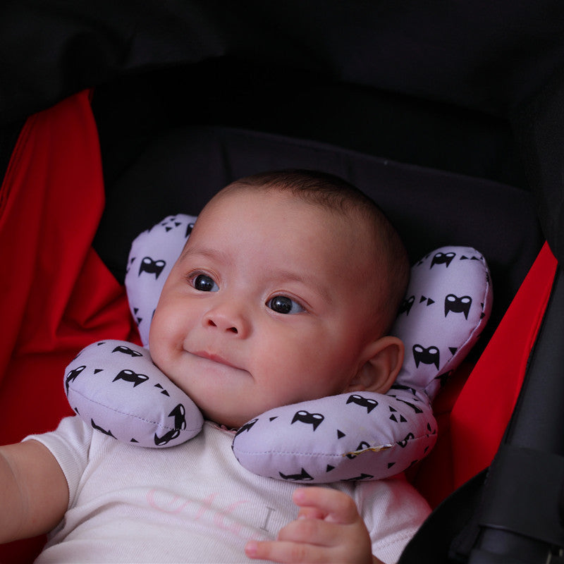 Baby in stroller wearing Côte & Crown U-shaped neck guard pillow with black and white pattern